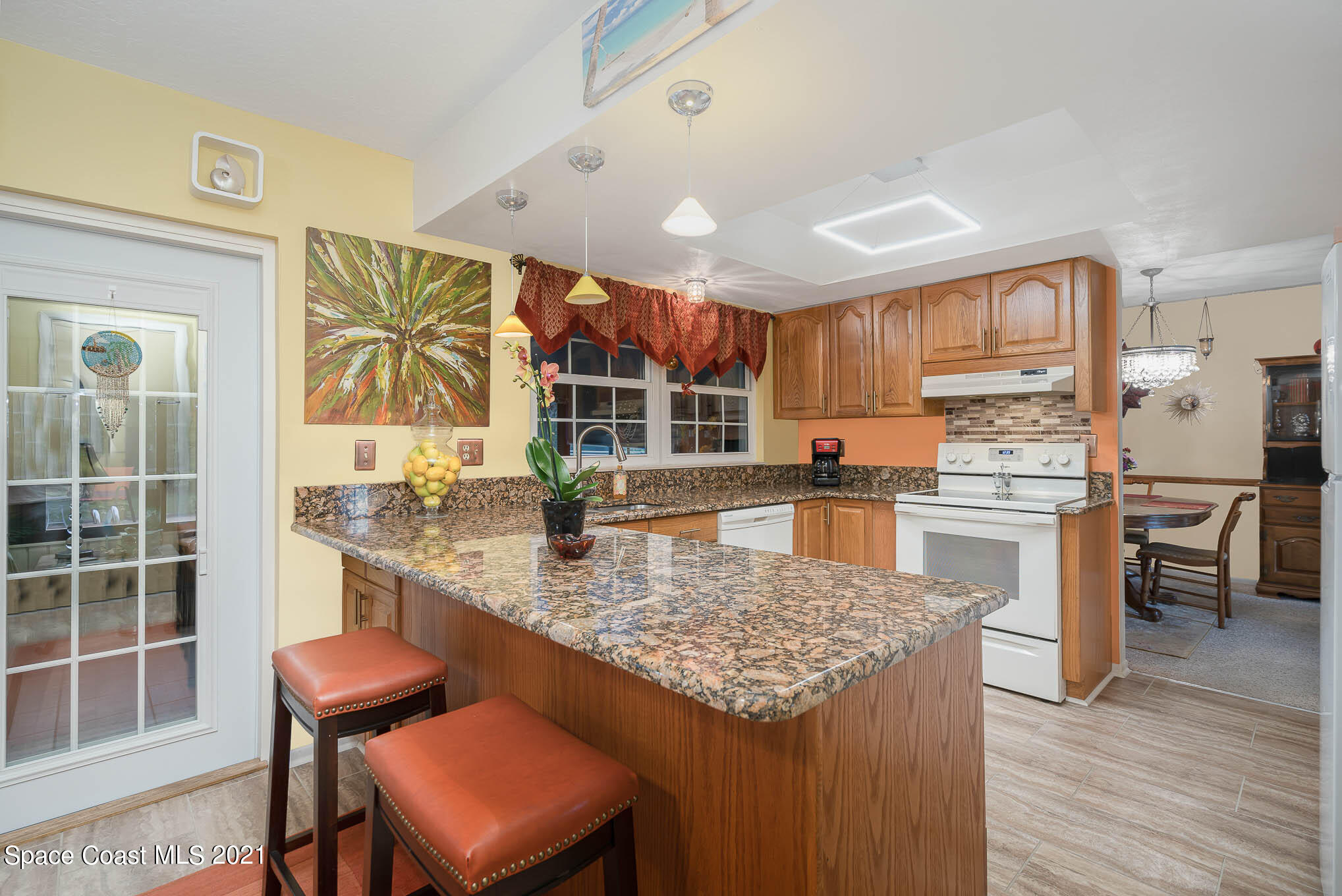 1291 Creel Road Northeast Palm Bay, FL 32905 - Photo 6 of 31 a kitchen with stainless steel appliances granite countertop a stove top oven a sink a dining table and chairs with wooden floor