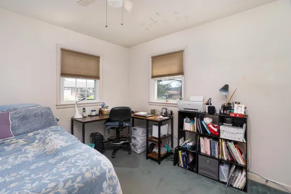 a bedroom with a bed a desk and book shelfs