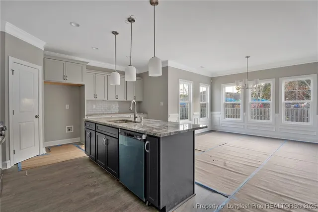 a kitchen with stainless steel appliances granite countertop a sink a stove and a wooden floor