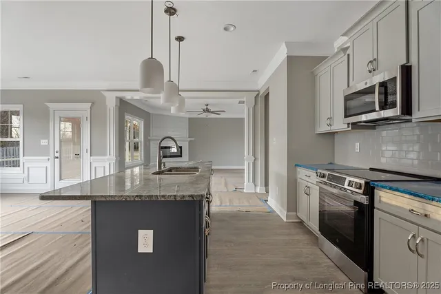 a kitchen with stainless steel appliances granite countertop a sink a stove and a wooden floors