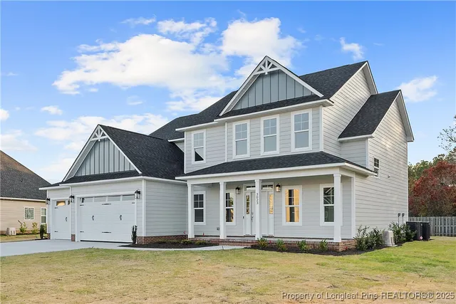a view of a white house with large windows next to a yard