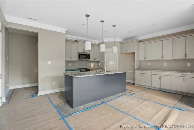 a kitchen with kitchen island granite countertop a stove a sink and white cabinets