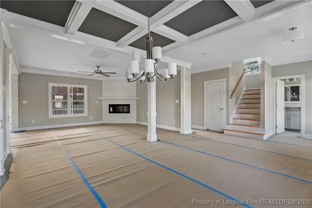 a view of an empty room with chandelier fan and fire place