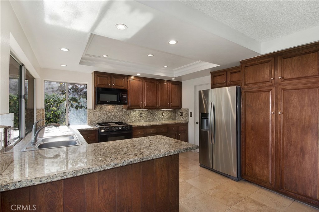 3808 Mistral Drive Huntington Beach, CA 92649 - Photo 3 of 28 a kitchen with stainless steel appliances granite countertop a refrigerator a stove and a sink with wooden cabinets