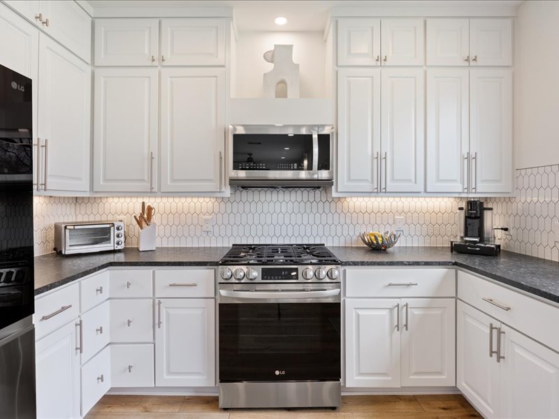 1205 South Main Street Georgetown, TX 78626 - Photo 7 of 35 a kitchen with granite countertop white cabinets and stainless steel appliances