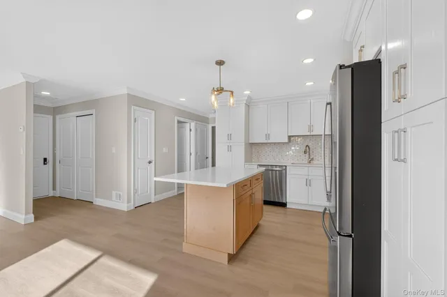 a kitchen that has a lot of white cabinets and stainless steel appliances