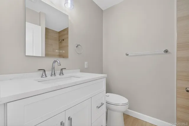 a bathroom with a toilet sink vanity and mirror