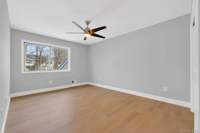 an empty room with window and ceiling fan