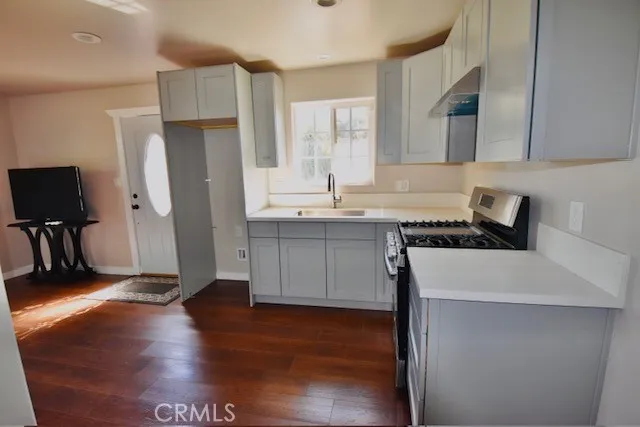 a kitchen with a sink a refrigerator and wooden floor