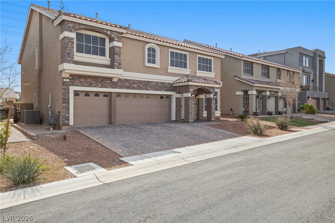 5953 Graystone Ridge Avenue Las Vegas, NV 89141 - Photo 3 of 51 Mediterranean / spanish house featuring stone siding, stucco siding, a garage, driveway, and a tiled roof