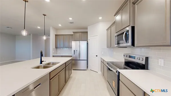 a kitchen with stainless steel appliances granite countertop a sink a stove and a wooden floors
