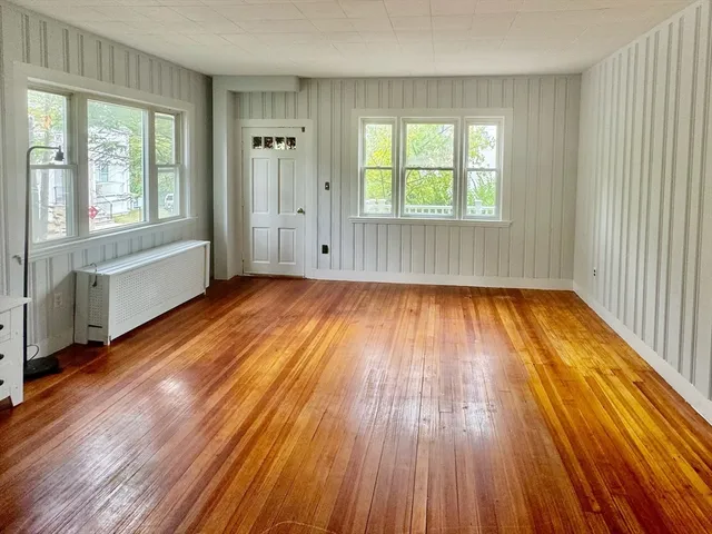an empty room with wooden floor and windows
