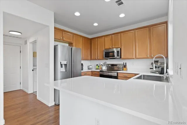 a kitchen with stainless steel appliances a refrigerator a sink a stove a microwave and wooden cabinets