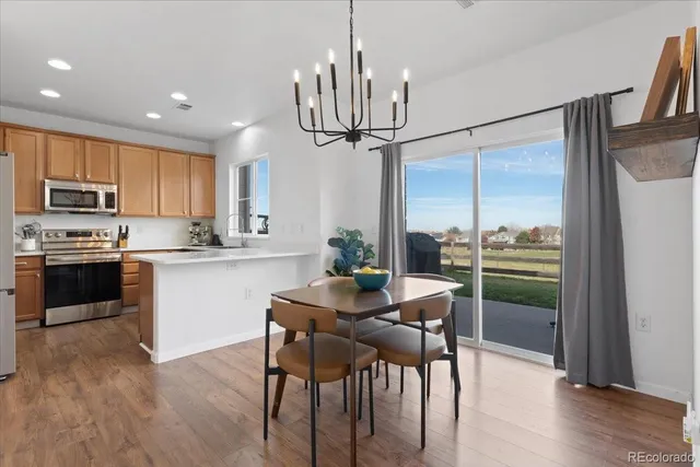 a kitchen with kitchen island granite countertop a refrigerator a stove a sink and a dining table with wooden floor