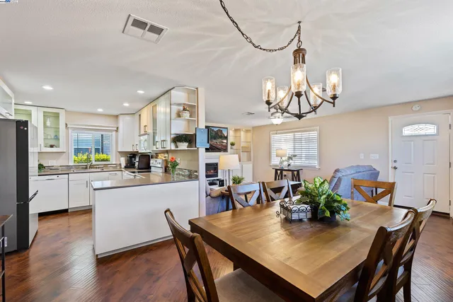 a view of a dining room and livingroom with furniture a chandelier and wooden floor