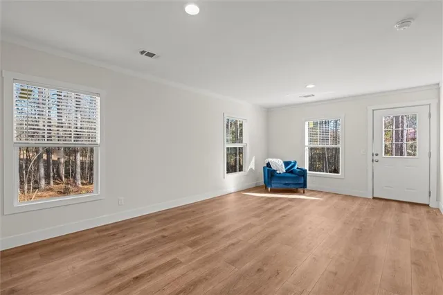 a view of an empty room with window and wooden floor