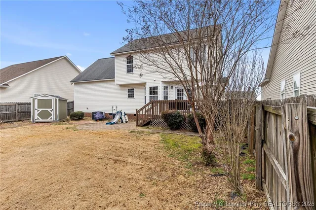 a view of a house with a barbeque and large trees
