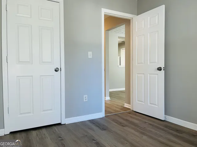 an empty room with wooden floor and closet area