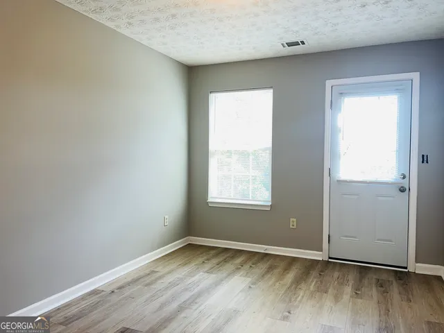 an empty room with wooden floor and windows
