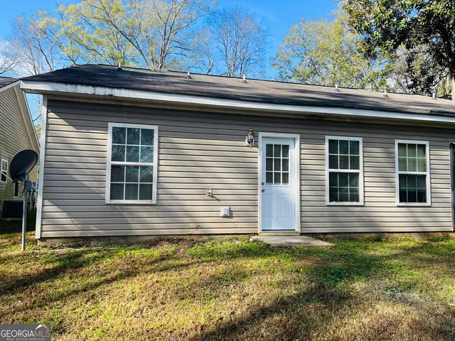 a brick house that has a small yard large trees