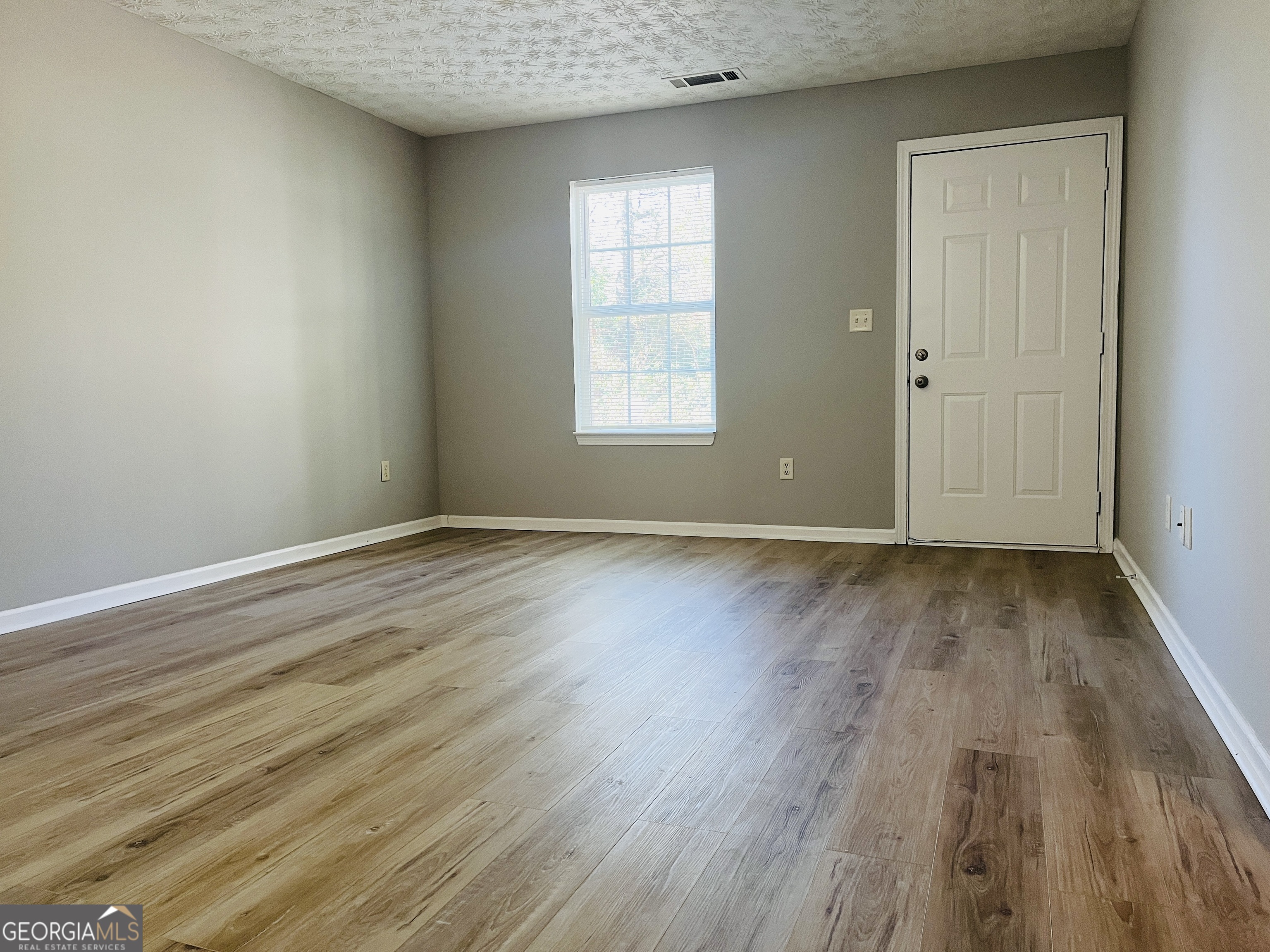 105 Granite Street, Unit B Hogansville, GA 30230 - Photo 4 of 28 an empty room with wooden floor and windows