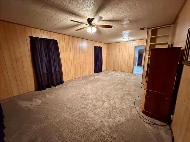 a view of a livingroom with a refrigerator a ceiling fan and wooden floor