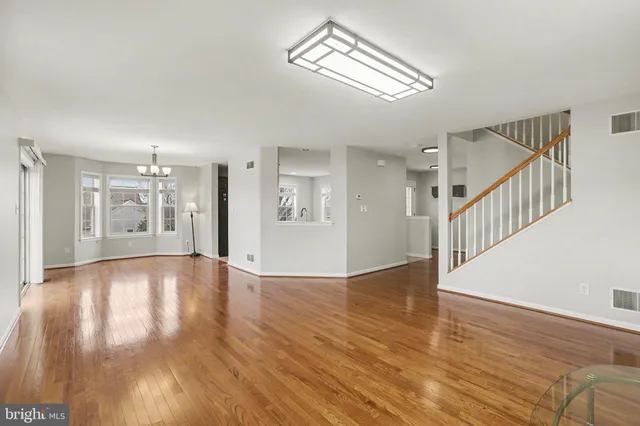 a view of an empty room with wooden floor and a ceiling fan