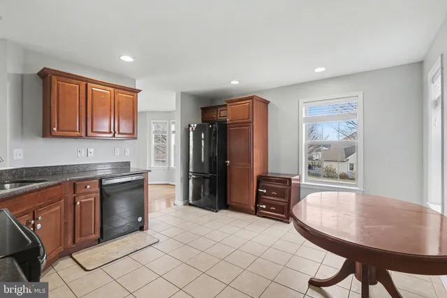 a kitchen with stainless steel appliances granite countertop a stove a refrigerator a sink a dining table and chairs with wooden floor