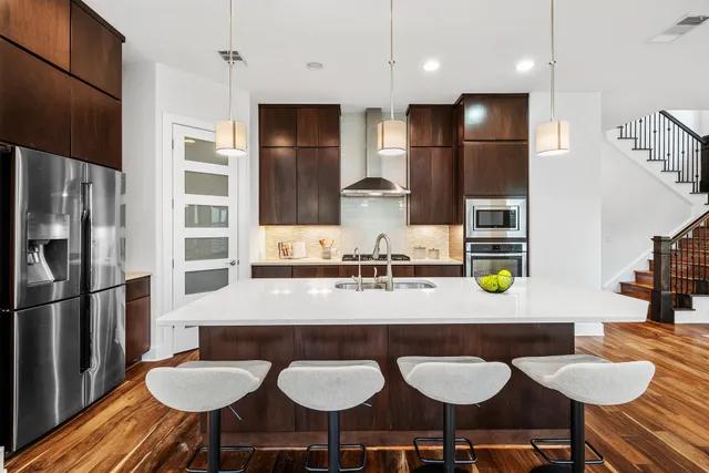 a kitchen with stainless steel appliances granite countertop a table chairs stove and refrigerator