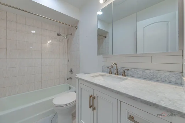 a bathroom with a granite countertop sink a toilet and bathtub