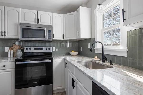 a kitchen with granite countertop white cabinets stainless steel appliances and a sink