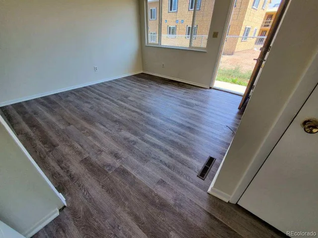 a view of an empty room with wooden floor and windows