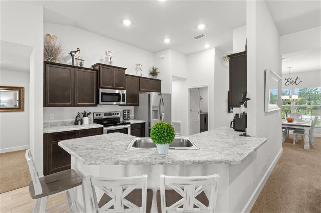 11042 Heth Court Weeki Wachee, FL 34613 - Photo 13 of 43 a kitchen with granite countertop kitchen island cabinets and refrigerator
