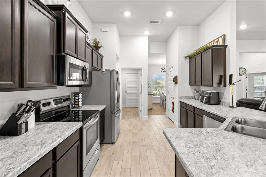 11042 Heth Court Weeki Wachee, FL 34613 - Photo 14 of 43 a kitchen with stainless steel appliances granite countertop a stove top oven a sink dishwasher a refrigerator and cabinets with wooden floor