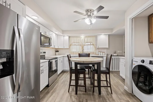 a kitchen with stainless steel appliances a stove a sink dishwasher a refrigerator with a dining table and chairs