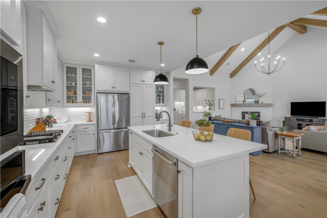 4309 Batona Court Bryan, TX 77802 - Photo 29 of 29 Kitchen with a kitchen bar, white cabinetry, open floor plan, decorative backsplash, and decorative light fixtures