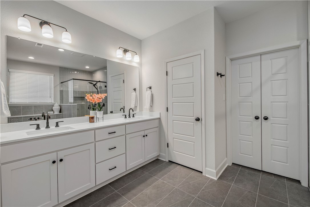 4309 Batona Court Bryan, TX 77802 - Photo 18 of 29 Bathroom featuring a stall shower, double vanity, and dark tile patterned floors