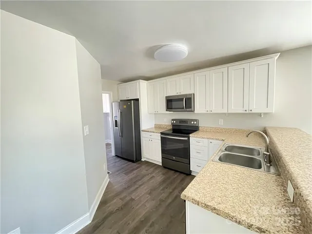 a kitchen with granite countertop a refrigerator stove and sink