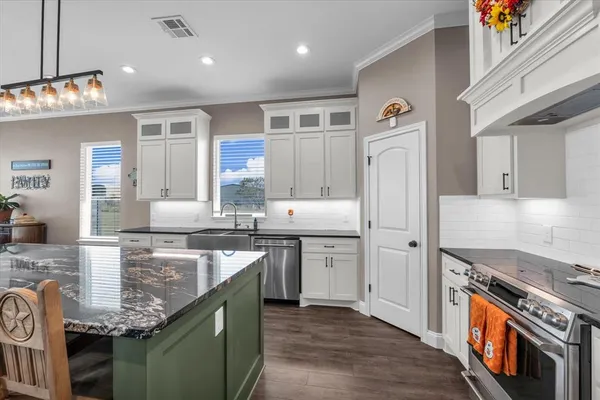 a kitchen with kitchen island granite countertop a stove and a sink