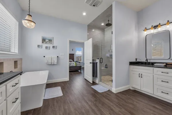 a large white kitchen with a refrigerator a sink dishwasher and white cabinets with wooden floor