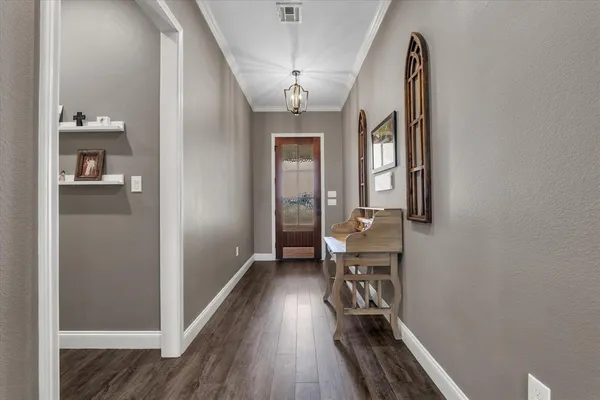 a view of a hallway with wooden floor and a bathroom