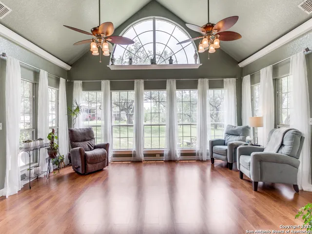 a living room with furniture large windows and a chandelier