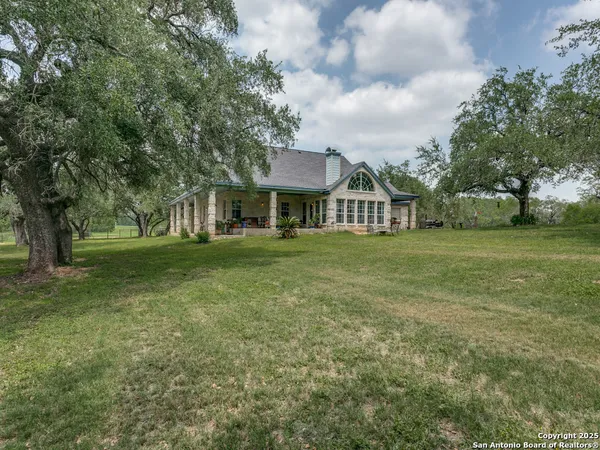 a view of a house with a big yard and large trees