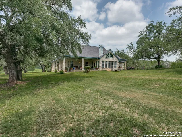 a view of a house with a big yard and large trees