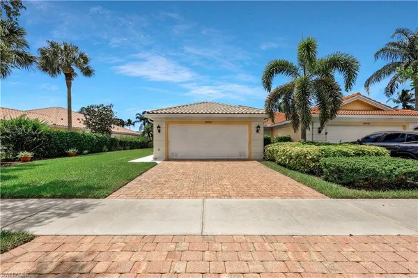 a front view of a house with a yard and palm trees