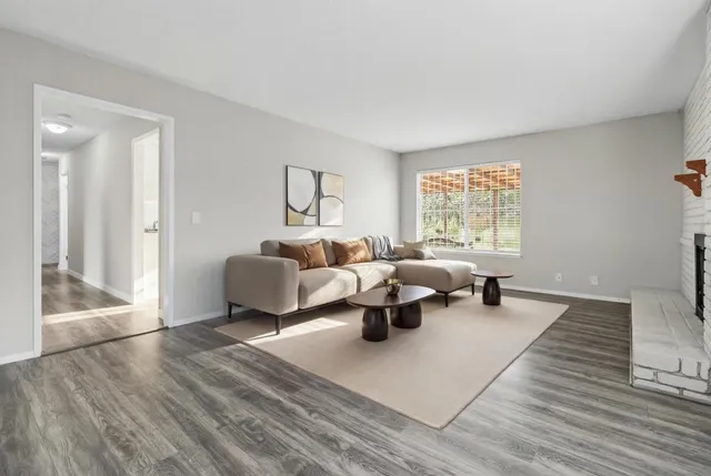an empty room with wooden floor windows and fire place