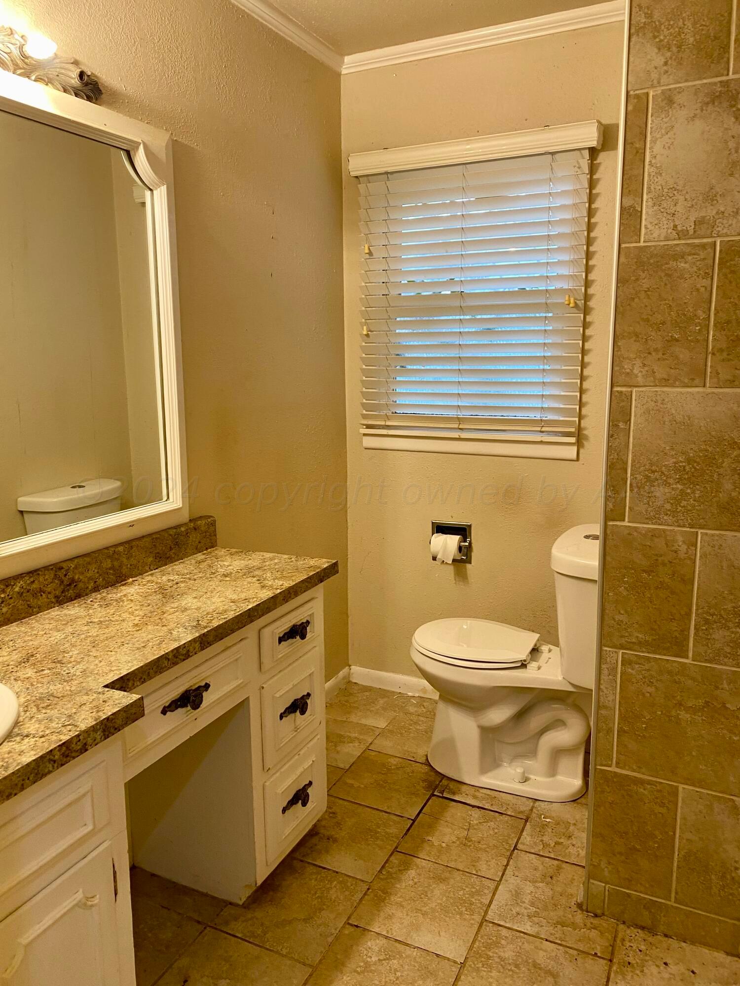 3309 Paramount Boulevard Amarillo, TX 79109 - Photo 18 of 26 a bathroom with a granite countertop toilet a sink and a shower
