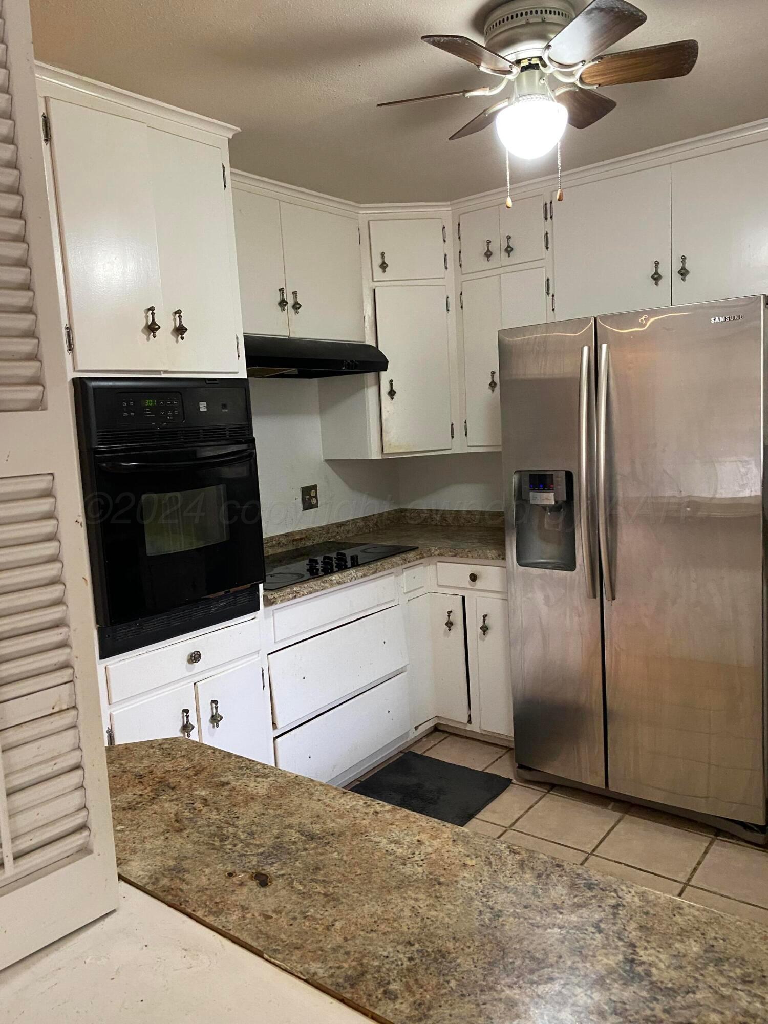 3309 Paramount Boulevard Amarillo, TX 79109 - Photo 5 of 26 a kitchen with stainless steel appliances kitchen island granite countertop a refrigerator a sink and white cabinets