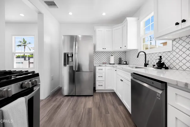 a kitchen with a sink wooden floor and stainless steel appliances
