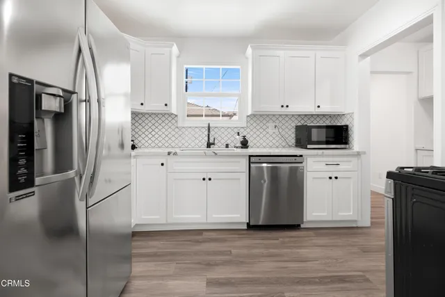 a kitchen with white cabinets stainless steel appliances and a refrigerator